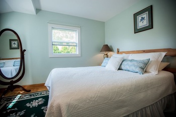 QUEEN BED WITH PILLOWS AND SMALL WINDOW