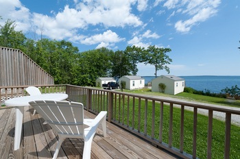 white chairs that are on a porch overlooking the water