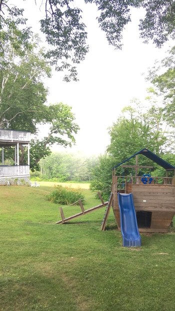 trees framing the green grass and ship playground