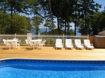 chairs sitting by a blue pool on wood deck