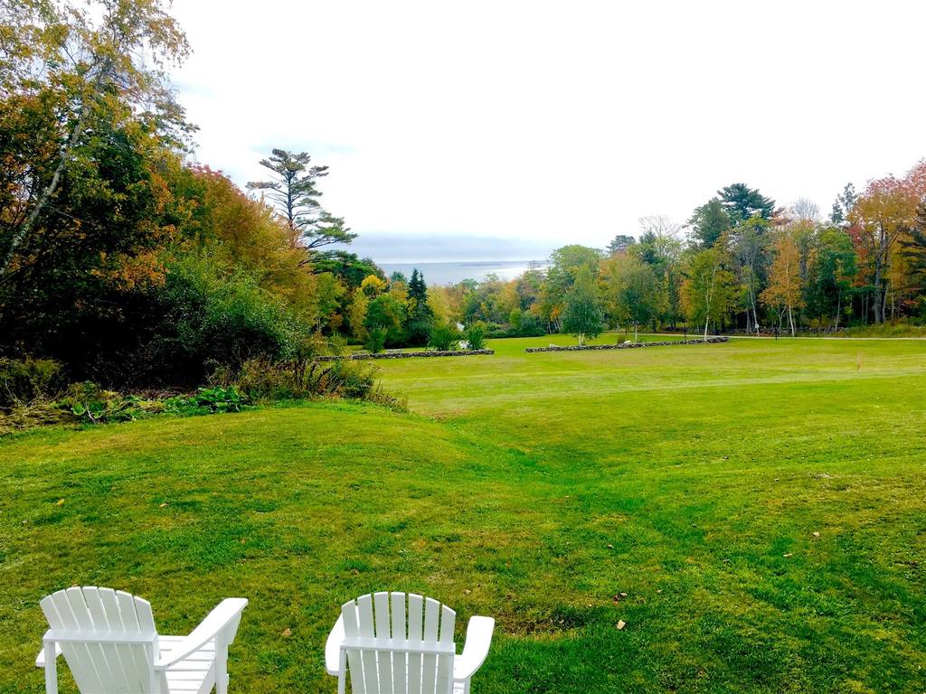 LARGE GREEN FIELD WITH WHITE LOUNGE CHAIRS