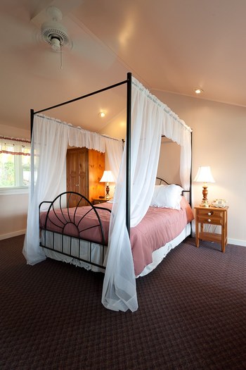 reddish carpet and a canopy bed in the room