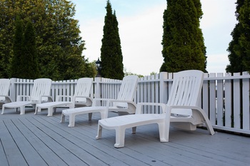 white lounging chairs sitting on the porch